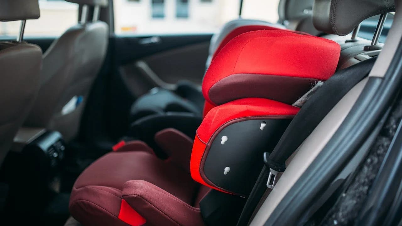 A red child car seat installed in a vehicle; no people present