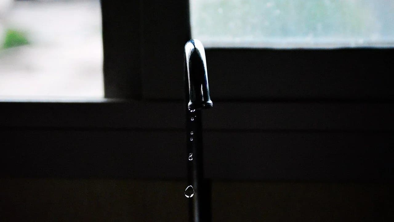 A water tap with drops of water falling; no people present