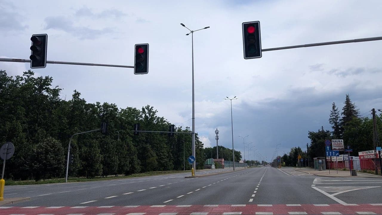 An empty signalized intersection with a zebra crossing and red bicycle lane; no people visible