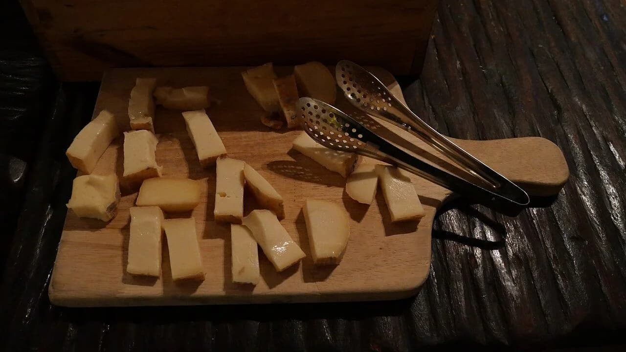 Sliced cheese arranged on a wooden cutting board