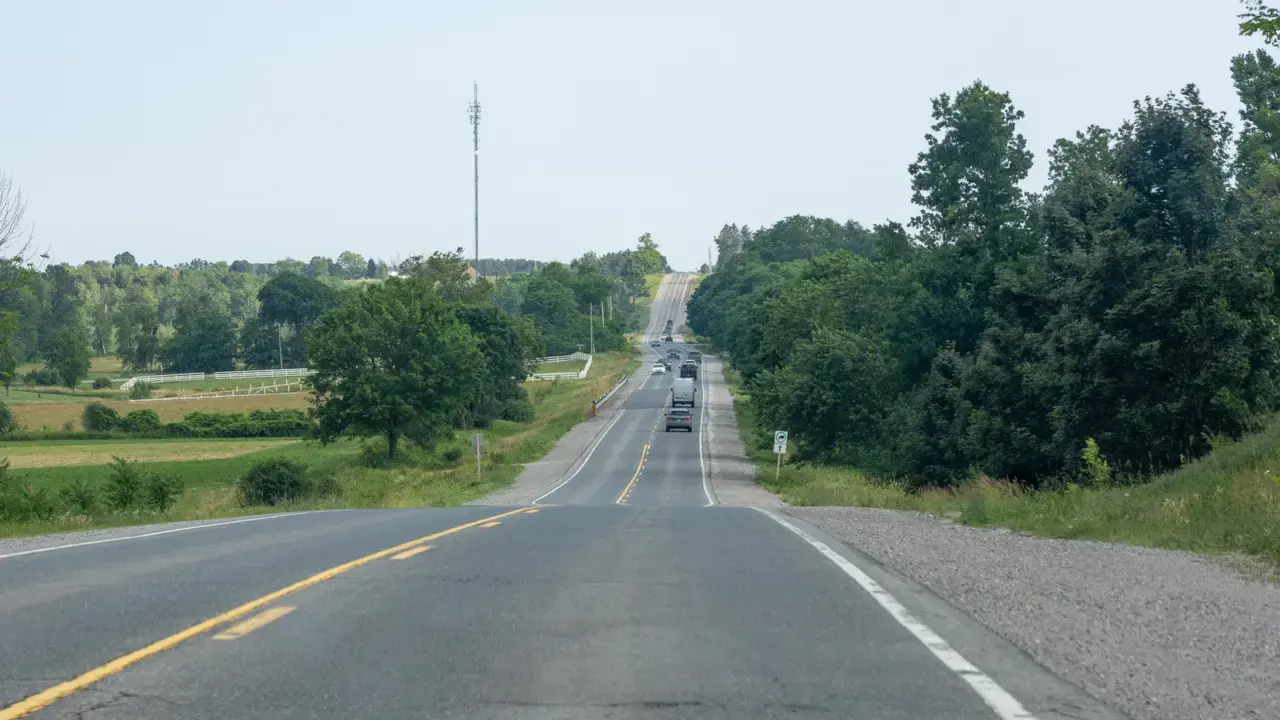 A two-lane rural road receding to the horizon with trees and fields on either side in Durham Region; no people visible. File photo of Lakeridge Road, not Concession Road 4 or Elliott Road in Clarington.