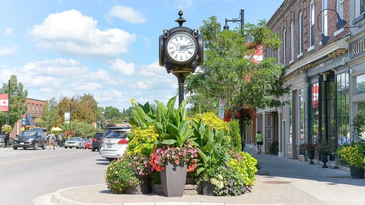 Downtown Uxbridge streetscape with historic clock, shops and trees; no identifiable people.