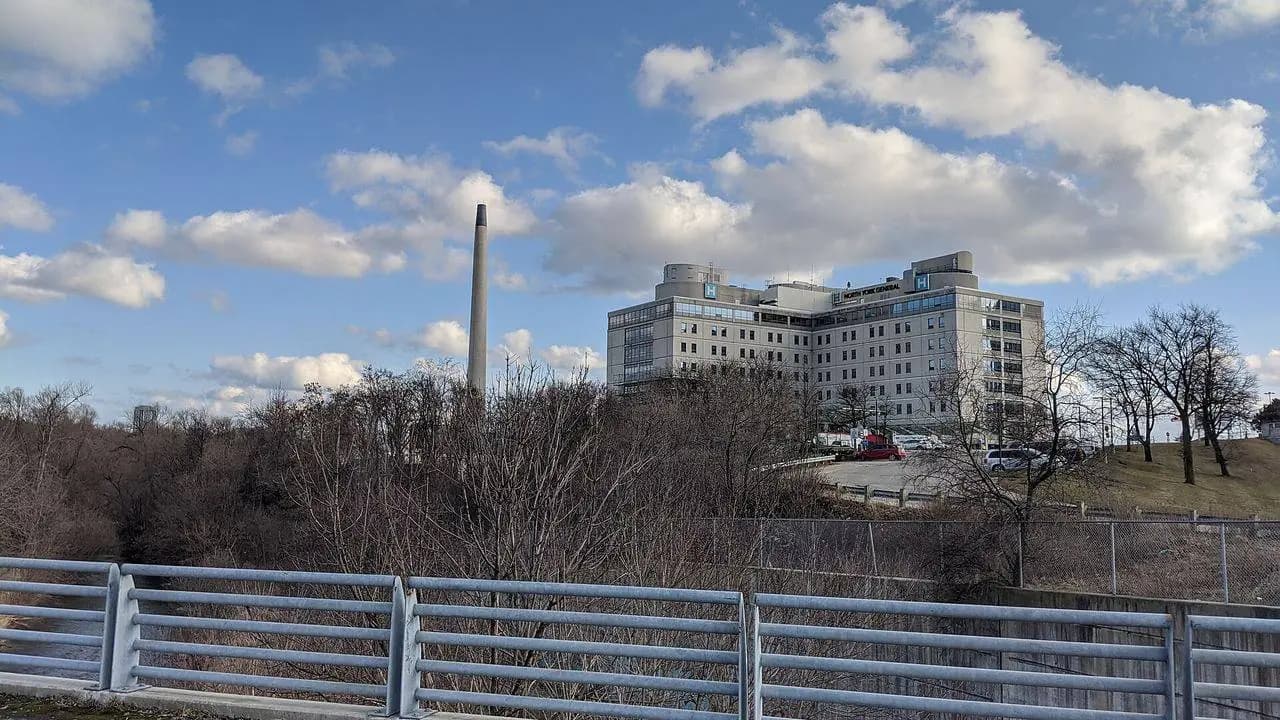 North York General Hospital in Toronto viewed from across a ravine, with a bridge railing in the foreground; no people visible.