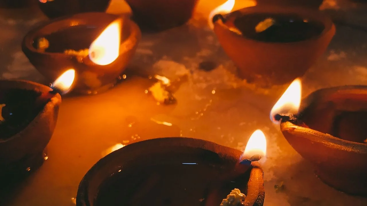 Close-up of lit clay diya oil lamps glowing in the dark.