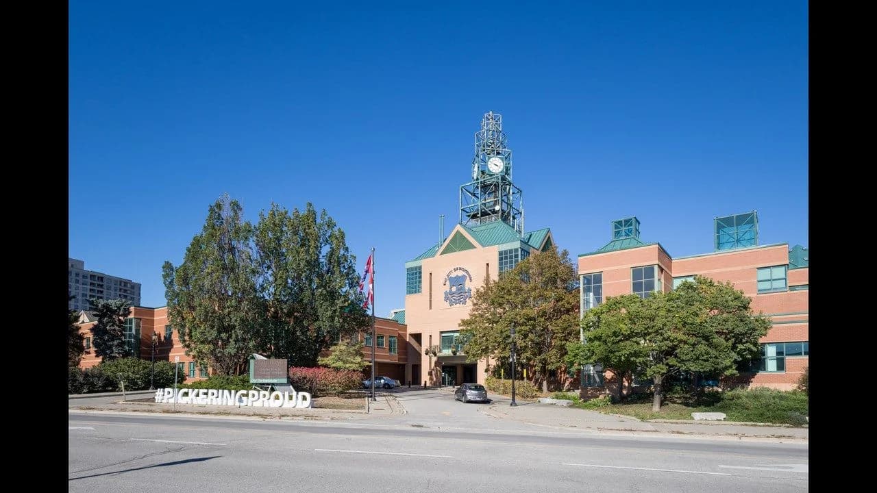 Pickering City Hall viewed from Glenanna Road on a clear day; modern civic building with clock tower, no people visible.