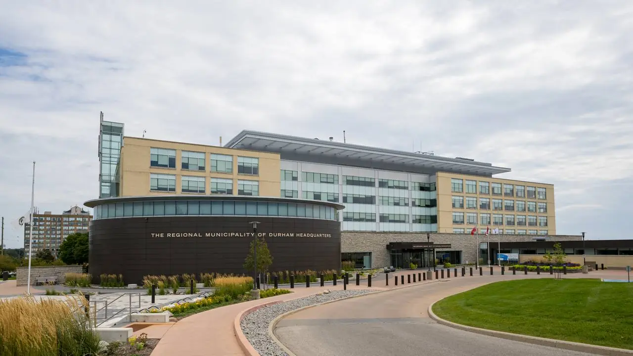 Durham Region Headquarters building in Whitby with driveway and lawn; no people visible.