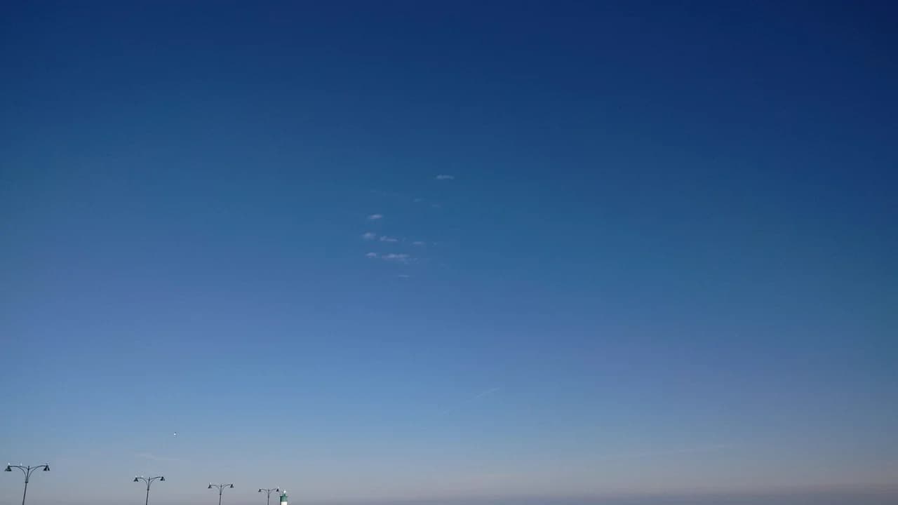 The lighthouse on the pier at Oshawa Harbour on Lake Ontario under a clear blue sky.