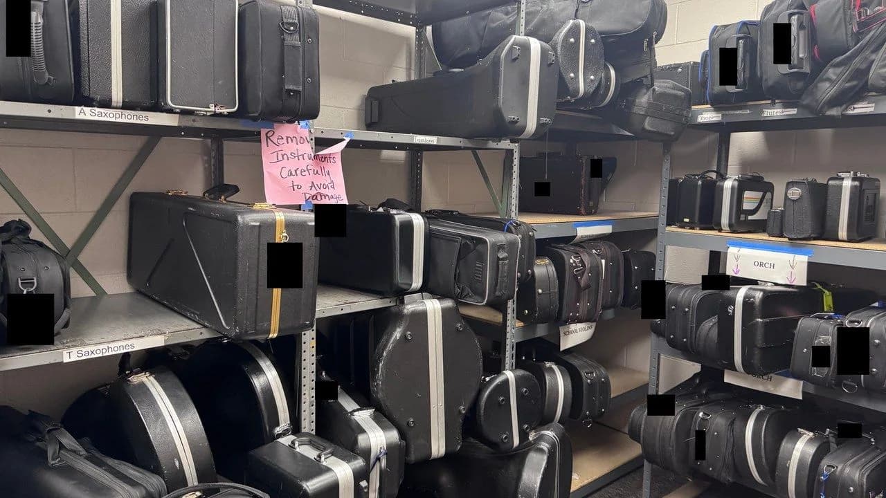 Shelves of band and orchestra instrument cases in a school music storage room; no people present