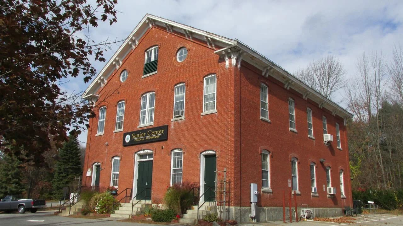 Brick two-storey senior community centre building with a Senior Center sign, photographed on a clear day; no people visible