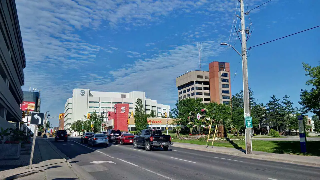 Street-level view looking east down King Street in Oshawa, Ontario, showing downtown buildings, cars, and street signs; no people visible.