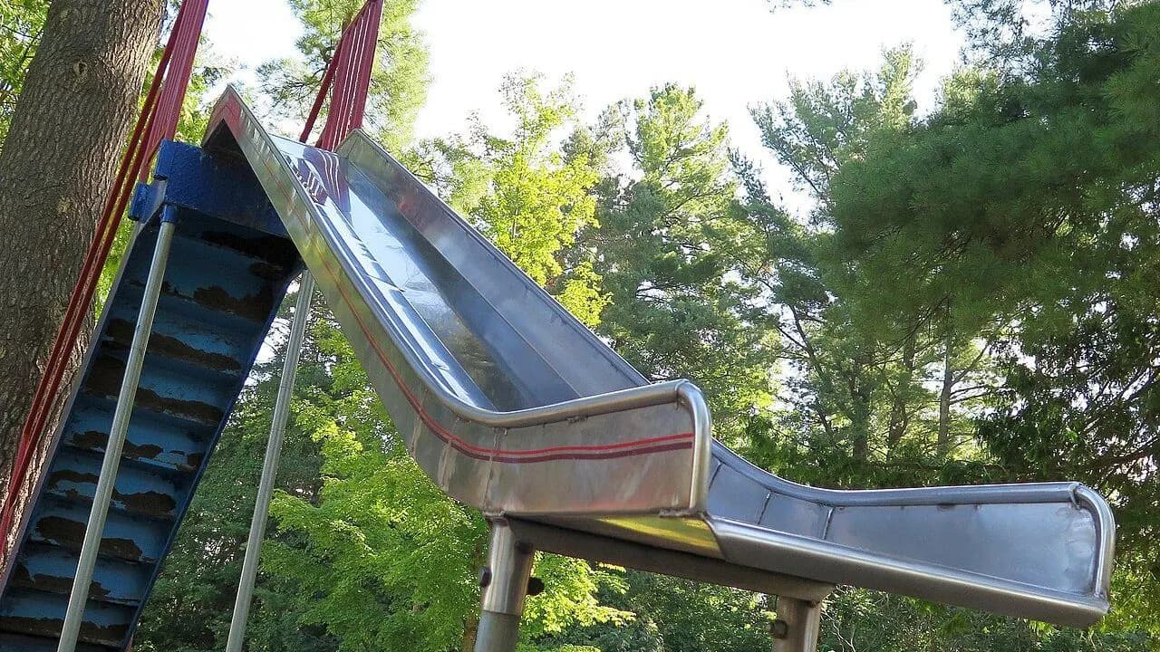 A metal playground slide in an Ontario park surrounded by trees