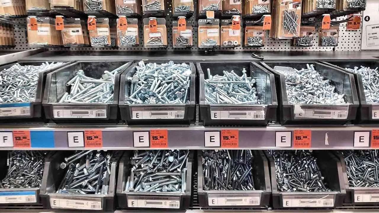 Bins of screws and bolts on shelves inside a hardware store; no people visible.