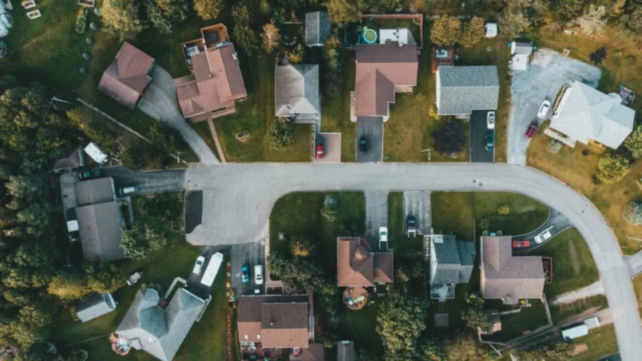 Aerial view of a suburban residential neighbourhood with curved streets, detached houses and green lawns.
