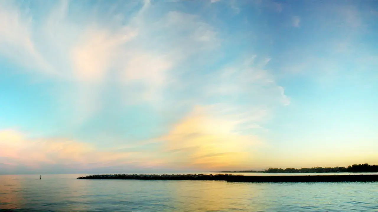 Calm Lake Ontario water beside the Whitby Harbour breakwater at sunset; no people visible.