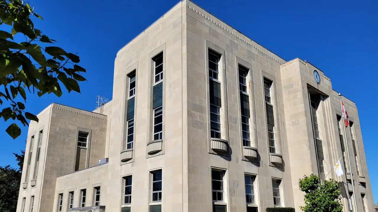 A stone courthouse building under a blue sky, photographed from a street corner; no people visible.